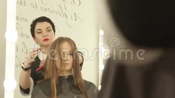 女理发师在理发店理发时用梳子梳长发关闭美发师视频的预览图