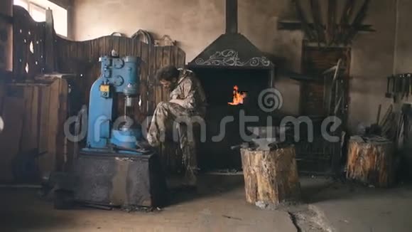 铁匠铺用工业压力机制造钢武器的有胡子的青年铁匠视频的预览图