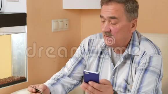 有胡子的老人从网上商店信用卡购买他坐在家里的沙发上视频的预览图