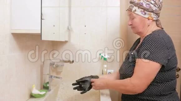 高级女人打扫酒店房间浴室的水槽她用手套和清洁剂在海绵的手里视频的预览图