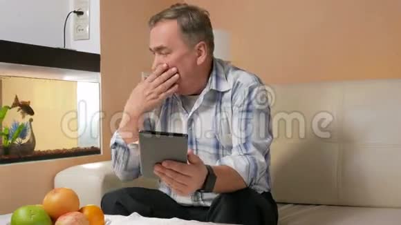 有胡子的老人咳嗽并在视频会议上与医生交流在线平板电脑上的医生视频的预览图