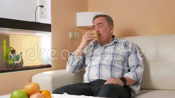 一个老胡子在家休息吃苹果他在水族馆看鱼吃水果视频的预览图