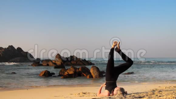穿黑色运动服的女孩在沙滩上练习瑜伽视频的预览图