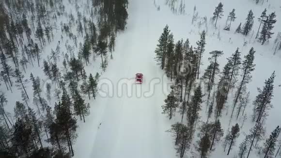在美丽的拉普兰冬季景观的道路上唯一的红色汽车在降雪期间的空中景观视频的预览图
