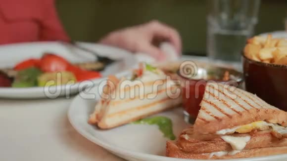女性手拿着otkusanny三明治在盘子里餐厅视频的预览图