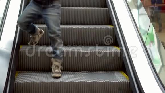 小男孩站在自动扶梯上这个男孩在购物中心的自动扶梯台阶上下来圣诞节购物慢慢视频的预览图