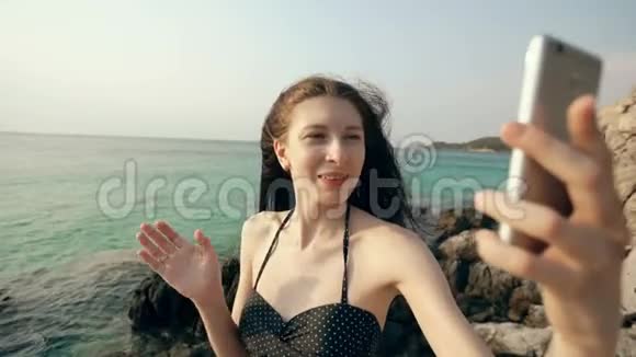 年轻快乐的女人在海边用智能手机上网和父母聊天视频的预览图