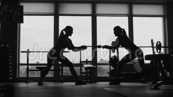 两个女人在体育健身馆拉绳子的剪影视频的预览图