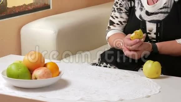 年老的女人在水族馆里吃苹果和看鱼桌子上有一盘不同的水果坐在里面视频的预览图