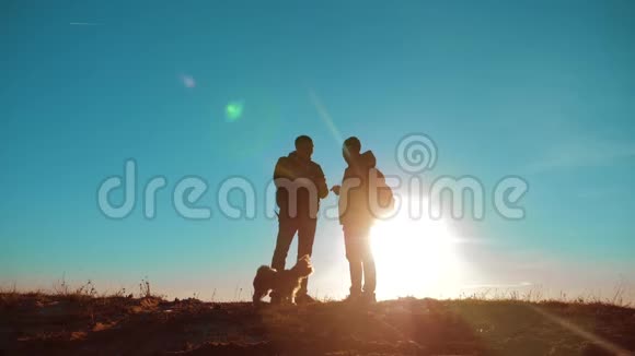 团队合作两名游客徒步旅行男人和狗带着背包在日落时去徒步旅行慢动作录像智能手机视频的预览图