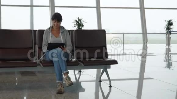 女子在机场等候区使用数码平板电脑视频的预览图