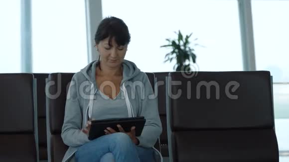 女子在机场等候区使用数码平板电脑视频的预览图