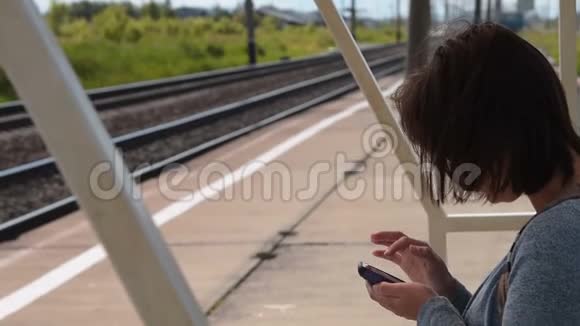 有手机的女旅客在站台上等候火车视频的预览图
