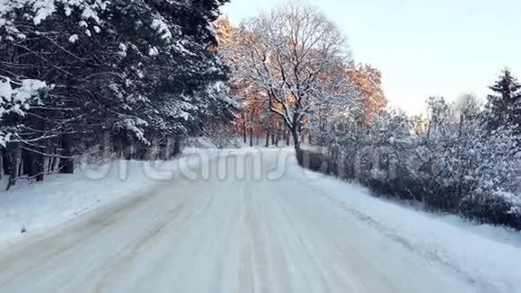 在寒冷的冬天平稳地沿着雪林路行驶立陶宛日落古达西亚4k视频的预览图