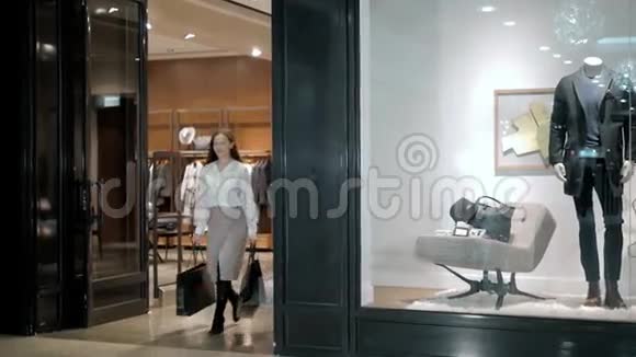 漂亮的商务女性穿着豪华西装在购物中心漫步时背着购物袋视频的预览图