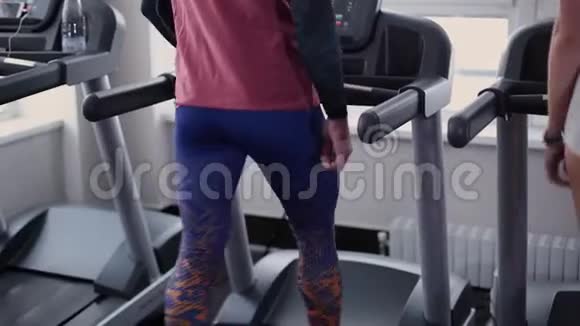 非常漂亮的健身模特和男人正在健身房的跑步机上训练视频的预览图