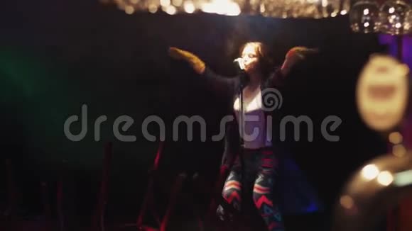 女清洁工在聚光灯下用麦克风在舞台上唱歌尖叫摇动头发视频的预览图