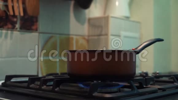 男人的手在厨房的炉子上用锅搅动饭菜视频的预览图