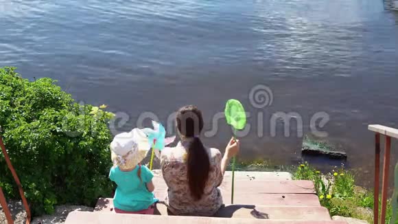 妈妈和小女儿坐在湖边的码头上视频的预览图