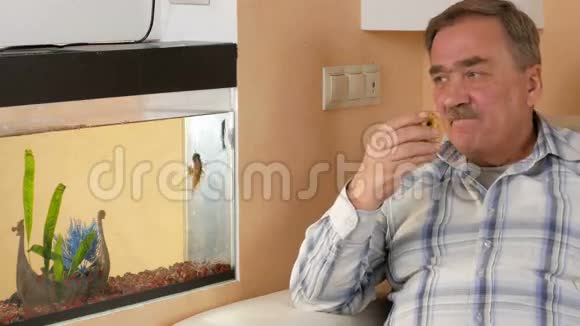 一个老胡子在家休息吃苹果他在水族馆看鱼吃水果视频的预览图