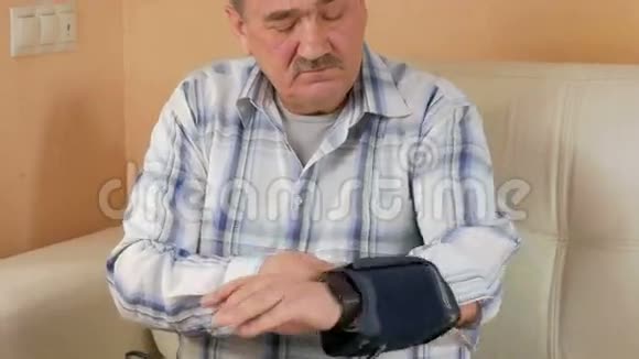 老人胡子本身测量家里的血压他坐在水族馆附近的沙发上小心翼翼地视频的预览图