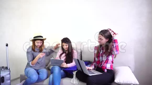 三个年轻的女姐妹使用小玩意互相交流白天坐在沙发上视频的预览图