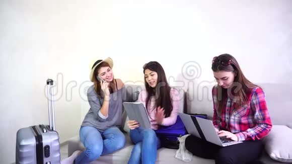 三个年轻的女姐妹使用小玩意互相交流白天坐在沙发上视频的预览图