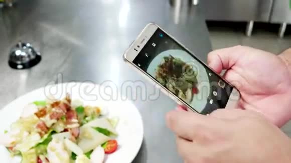 手机屏幕上的凯撒沙拉厨师在餐厅的专业厨房里拍照食物照片食物移动视频的预览图