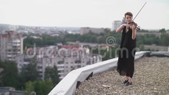 美丽的年轻女子在屋顶上小提琴演奏视频的预览图