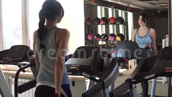 年轻女子在健身房的跑步机上行走健身房的有氧运动视频的预览图