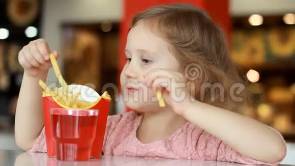 小女孩在咖啡馆里吃快餐炸薯条肖像特写视频的预览图
