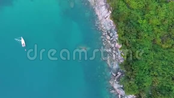 小游艇在清澈的蓝色水域旁边的秘密努伊海滩与石头和棕榈树泰国普吉岛高清天线视频的预览图