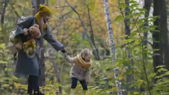 小女儿和妈妈在秋天公园散步玩树叶视频的预览图