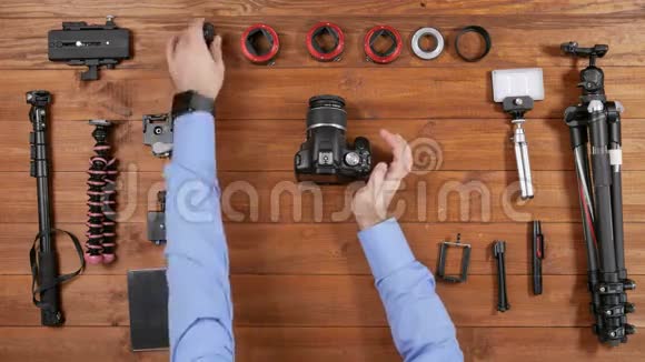 双手男性摄影师把相机放在球头上每条腿都打开和关闭木桌顶景视频的预览图