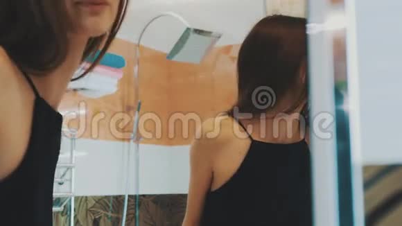 年轻的黑发女孩在浴室的镜子前刷牙下沉微笑视频的预览图