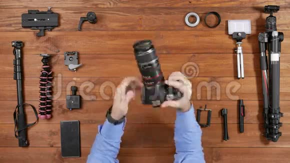 男性摄影师从相机里拿出一个宏观镜头和额外的戒指木桌顶景拍摄设备视频的预览图