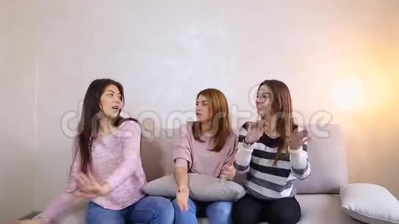 有趣的女孩听音乐和舞蹈微笑在他们的脸上坐在沙发背景的轻墙在房间里视频的预览图