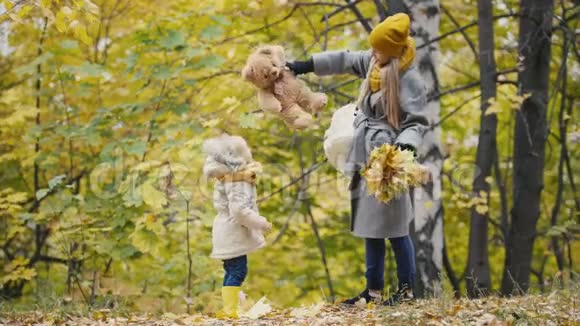 快乐的小女儿和妈妈熊泰迪一起走在秋天的公园里视频的预览图
