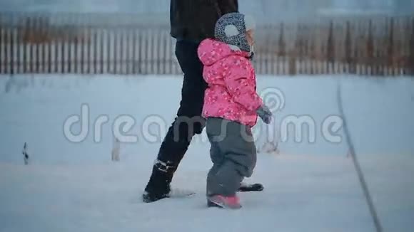 冬天的晚上爸爸和他的小女儿手拉手在公园里散步视频的预览图