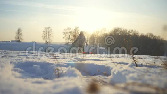 年轻开朗的女人在冬天缓慢地穿过太阳在山上奔跑1920x1080视频的预览图