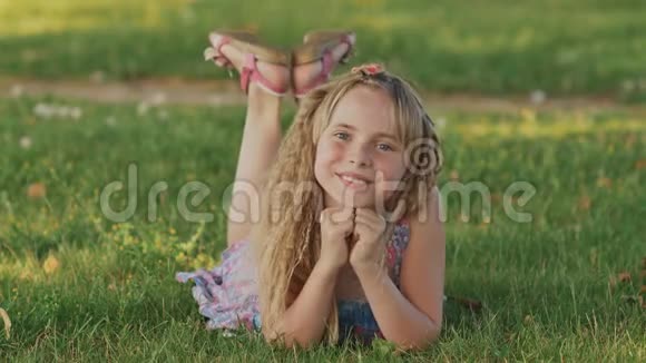 美丽的金发女孩躺在田野上绿草如茵户外享受自然绿色健康的微笑女孩视频的预览图