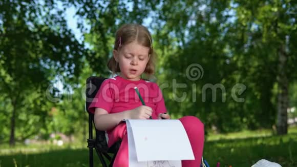 夏天在公园户外画铅笔的小女孩的肖像视频的预览图