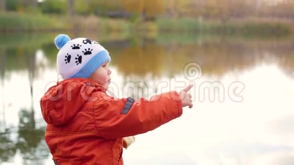 一个孩子站在池塘的岸边扔石头在新鲜空气中游走视频的预览图