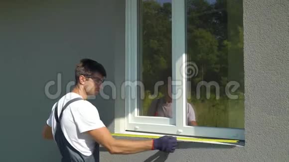 戴安全眼镜和防护手套的男工测量外窗台和PVC窗框尺寸视频的预览图