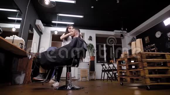 在时尚的理发店做时尚的发型男臀和女理发师视频的预览图