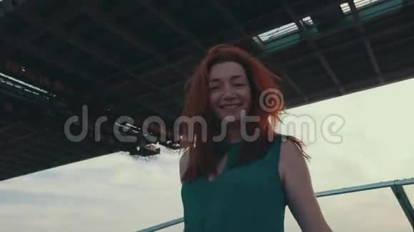 红发幸福少女在桥下的摩托艇上航行夏日之夜视频的预览图