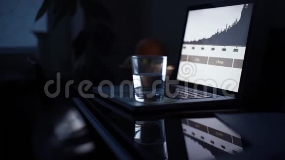 晚上男人在厨房用笔记本电脑桌子上有一杯水和铅笔视频的预览图