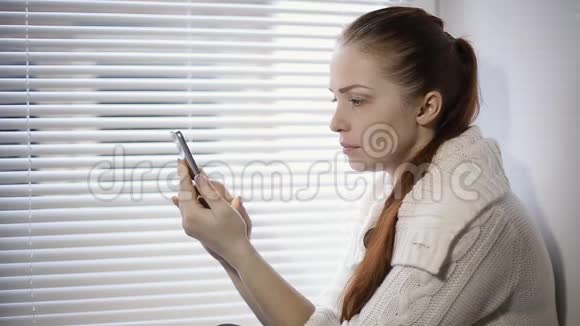 网上购物一名年轻女子在智能手机屏幕上浏览网上商店的商品视频的预览图