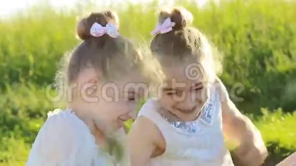 两个小女孩坐在草地上聊天玩得开心视频的预览图