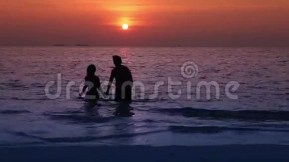 男人和女人的剪影日落时离开大海视频的预览图